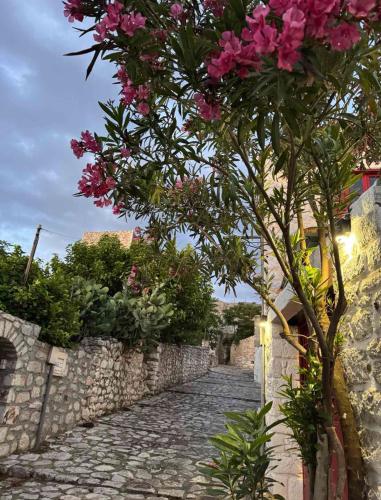 a tree with pink flowers on a stone road at Lithos Areopoli Traditional House in Areopolis