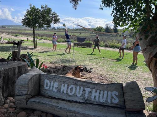 a dog laying on a sign in a park with people at Merwespont Guesthouses#DieHouthuis#Die Wyntenke#A Snoozer's Cottage# in Bonnievale