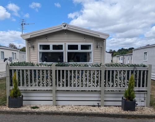 a small house with a wooden fence in front of it at Casita De Cuervo at Shorefield Park - WIFI - Pet Friendly - Passes Included in Everton