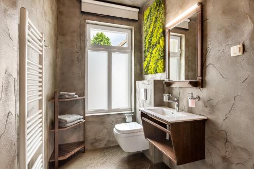 a bathroom with a toilet and a sink and a window at Guest House The Hive in Bled