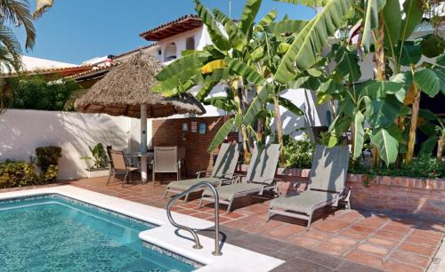 a pool with chairs and an umbrella next to a house at Aventura Pacifico Boutique Suites & Villas in Bucerías