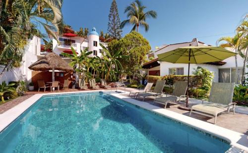 a swimming pool with chairs and an umbrella next to a house at Aventura Pacifico Boutique Suites & Villas in Bucerías