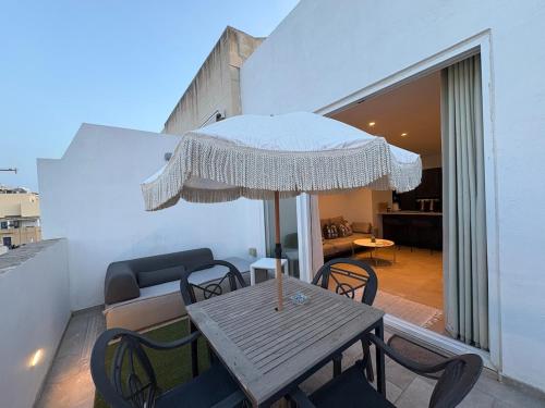 a wooden table and chairs with an umbrella on a balcony at Cute little Penthouse in the Heart of Sliema in Sliema