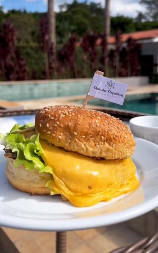 a hamburger on a white plate on a table at Vale das Orquídeas Pousada in Socorro