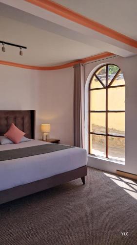 a bedroom with a bed and a large window at Casa Encuentro San Blas in Cusco