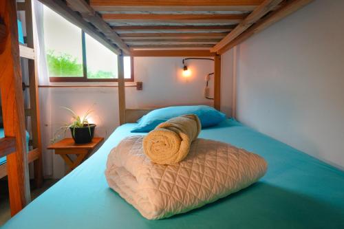a bed with a rolled up towel on top of it at Hermanos Perdidos Surf in Las Tunas