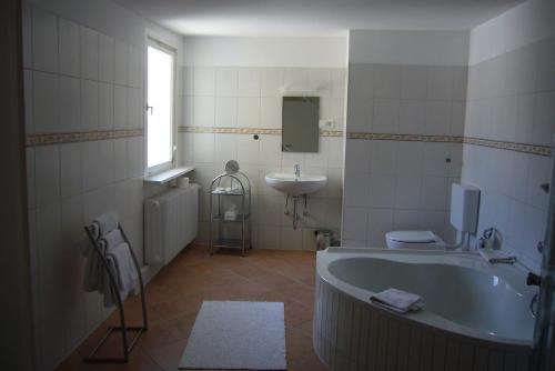 un bagno bianco con vasca e lavandino di Hotel am Friedrichsbad a Baden-Baden