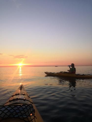 a person sitting on a kayak in the water at sunset at SEA and SUN Ankaran, near the Beach, free Parking and Wi-Fi, stunning sunset, 80m2 in Ankaran