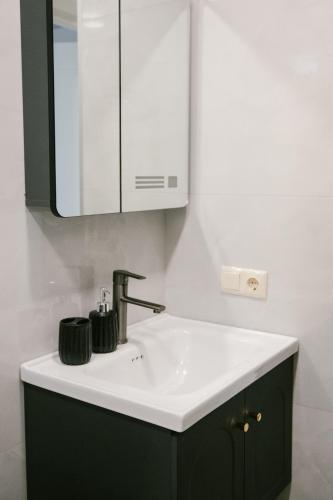 a bathroom with a sink and a mirror at Batumi Apartment with Cozy Yard in Batumi