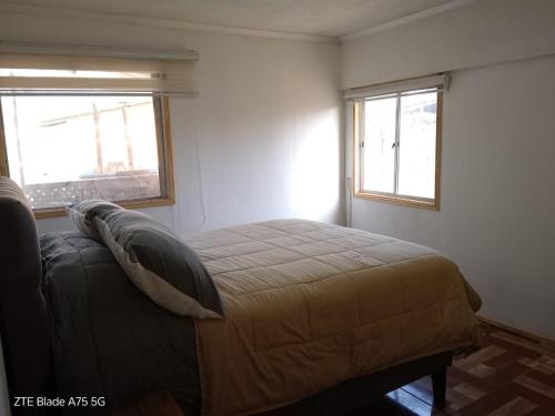 a bedroom with a bed and two windows at Casa Niwa koi Entre Peces en Paine in Paine