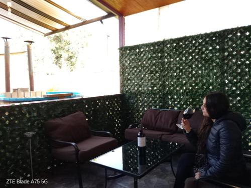 a woman sitting at a table with a glass of wine at Casa Niwa koi Entre Peces en Paine in Paine