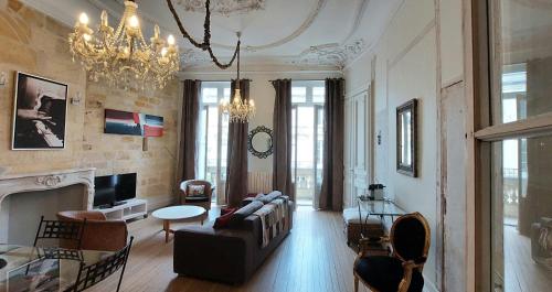 a living room with a couch and a chandelier at Burdigala Homes - Appart Duffour Dubergier in Bordeaux