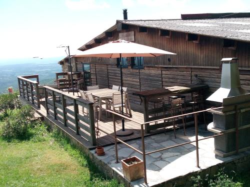 a wooden deck with tables and an umbrella at La Ferme Du Maquis in Antisanti