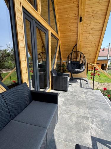 a porch with a couch and chairs on a house at Cabana Bucegi View A-Frame Bran in Predeluţ