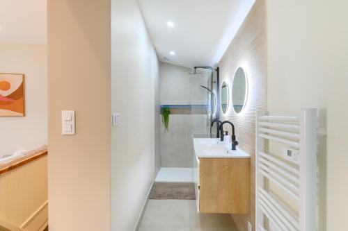 une salle de bain blanche avec un lavabo et une douche dans l'établissement Les Pierres dorées - Moderne & Confort, à La Roche-sur-Yon