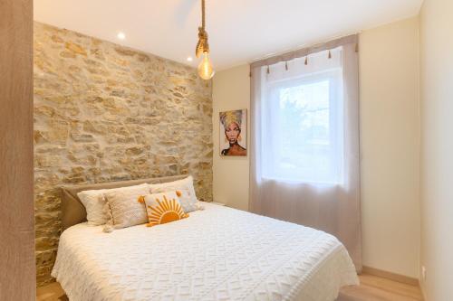 - une chambre avec un lit blanc et un mur en pierre dans l'établissement Les Pierres dorées - Moderne & Confort, à La Roche-sur-Yon