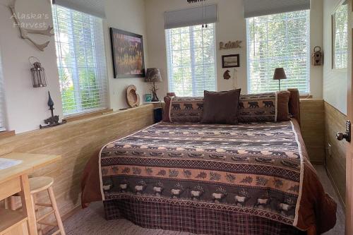 a bedroom with a bed and a table and windows at Alaska's Harvest Bed and Breakfast and Luxury Log Cabin in Palmer