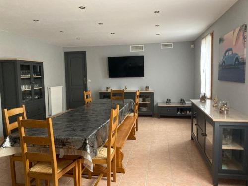 une salle à manger avec une table avec des chaises et une télévision dans l'établissement Gîte Les Chalottières - 12 pers avec bain nordique, à Changé