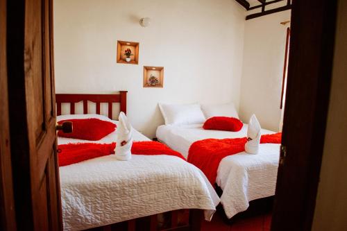 two beds in a room with red and white sheets at Apartahotel Casa de Angel in Villa de Leyva