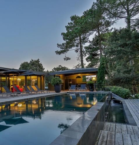 une piscine avec des chaises et une maison dans l'établissement maison traditionnelle avec belle vue, à Seignosse