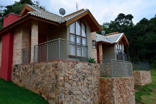 a house with a stone wall in front of it at Hotel Pousada Água Da Mina in Monte Sião