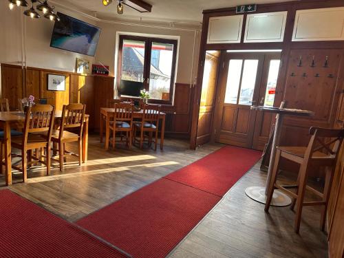 a restaurant with wooden tables and chairs and a red rug at Monteurzimmer in Tresdorf
