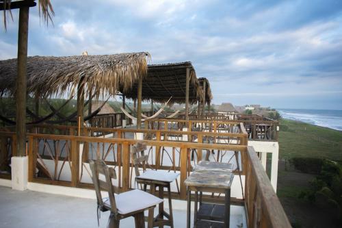 a restaurant with chairs and a thatched roof and the ocean at Nativa Beach Front in Sipacate