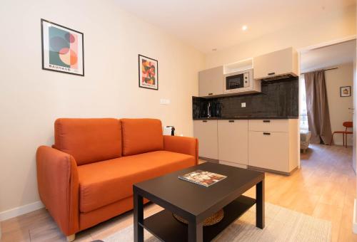 un salon avec un canapé orange et une table dans l'établissement Le petit Haussmann, à Clichy