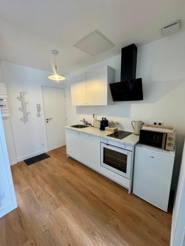 une cuisine avec des appareils électroménagers blancs et du parquet dans l'établissement Les Chouettes, au Mans