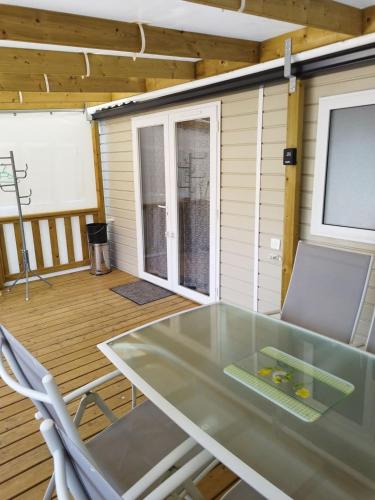 d'une terrasse avec une table en verre et des chaises. dans l'établissement Mobil-home 