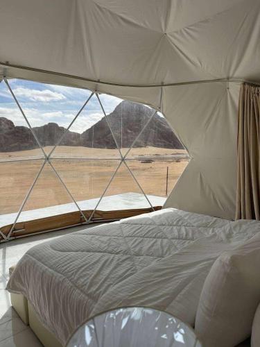 a bed in a tent with a view of the desert at Rum Royal Dunes Camp & tour in Wadi Rum