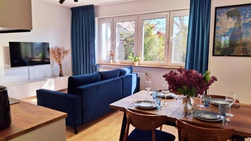 a living room with a dining table and blue chairs at Rumia Cichy Zaułek 2 in Rumia