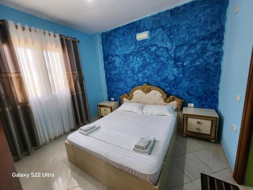a bedroom with a bed with a blue wall at Villa Arilena in Sarandë