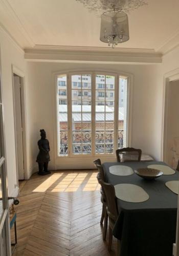 une salle à manger avec une table et des chaises et une fenêtre dans l'établissement Appartement typiquement parisien, à Paris