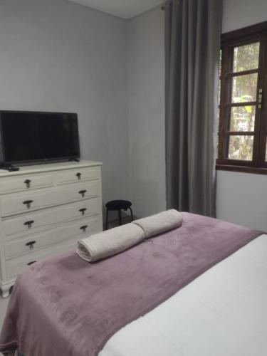 a bedroom with a bed and a dresser with a television at Armazém do Porto Chalé Ixora in Morretes