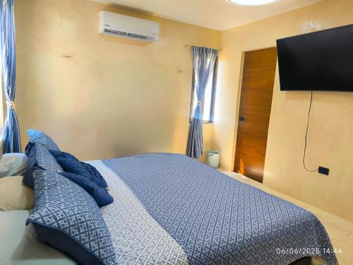 a bedroom with a bed and a flat screen tv at Agua Azul Chicxulub Puerto in Chicxulub