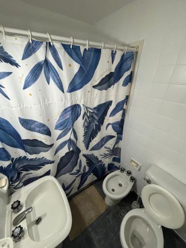 Un baño con inodoro y una cortina de ducha azul y blanca. en Wu Wey, en Miramar