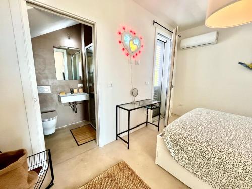a bedroom with a bed and a bathroom with a sink at Dimora Vereto in Morciano di Leuca