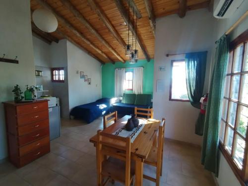 a living room with a table and a kitchen at Casas HG-Desayuno sencillo entregado al check in-Pileta climatizada en predio a 2 kilómetros-Acepta mascotas bajo petición-Cochera para 1 auto in Huerta Grande