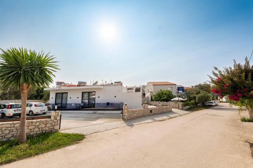 a house with a palm tree in front of a street at ABOJA Inn in Ksamil