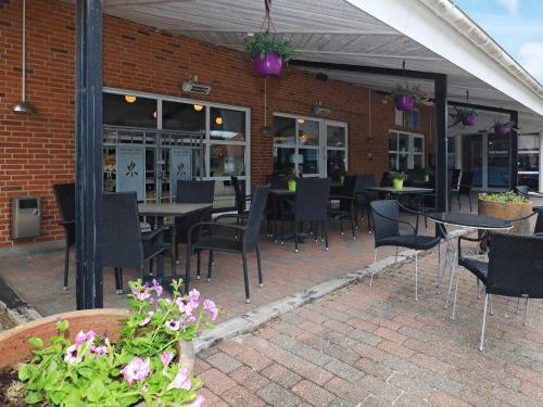 a patio with tables and chairs and a building at 4 person holiday home on a holiday park in Blåvand in Blåvand