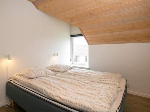 a bedroom with a large bed with a wooden ceiling at Ho Holiday Center in Blåvand