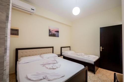 sypialnia z dwoma łóżkami z białą pościelą w obiekcie Guesthouse A&F w mieście Ksamil