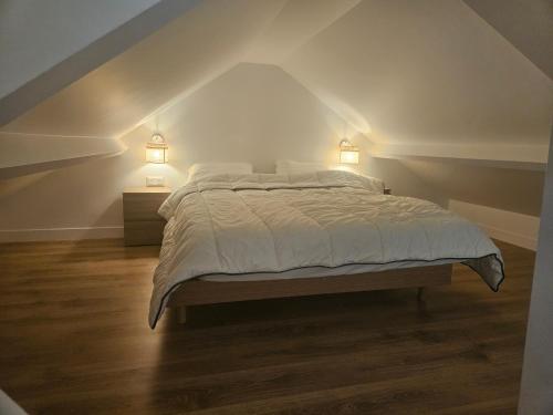 a bedroom with a bed with two lights on the wall at Chez Clark et Elo in Bréançon