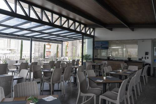 a restaurant with tables and chairs and windows at Hotel Principal in Mexico City