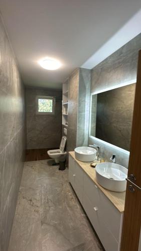 a bathroom with two sinks and a toilet and a mirror at Villa Pazaric in Resnik