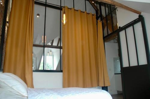 a bedroom with a bed and a window with yellow curtains at Nid Élégant - Vue Chapelle et Mer in Étretat
