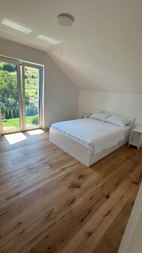 a white bedroom with a bed and a wooden floor at Villa Pazaric in Resnik