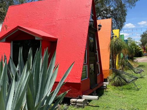 a red building with a red door next to a plant at Memorias Teotihuacán in San Sebastian Xolalpa