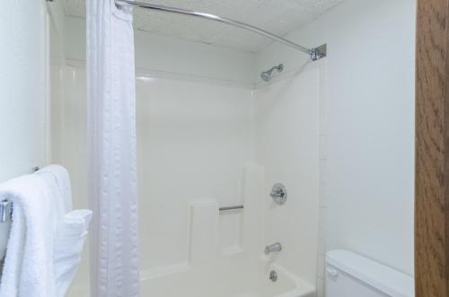 a white bathroom with a shower with a shower curtain at Baymont by Wyndham Gillette in Gillette